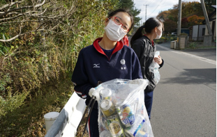通学路の空き缶をボランティア袋いっぱいに拾った女子生徒の写真