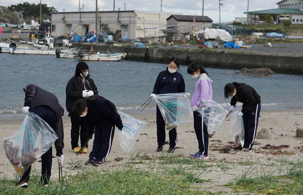 大久喜海岸でボランティア袋とトングを手にごみを拾う女子生徒の写真