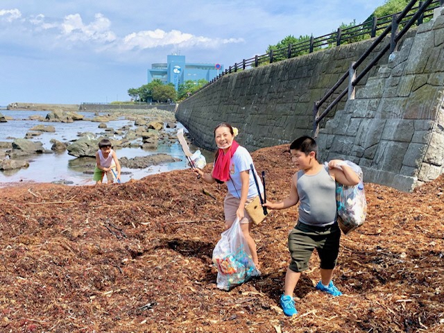 マリエント前岩場で、ボランティア用ごみ袋いっぱいにごみを拾う子どもと女性