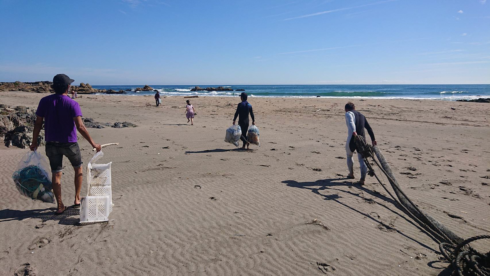 海岸砂場で拾ったごみや漁網を運ぶ五人の様子
