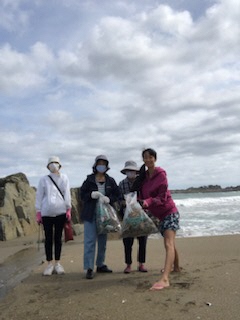 海をバックに集めたごみ袋を手に4人で集合写真