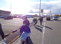 参加した多くの人がボランティア袋を手に歩道を歩いている