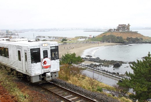 JR八戸線から見た蕪島海水浴場と走行中の車両の写真