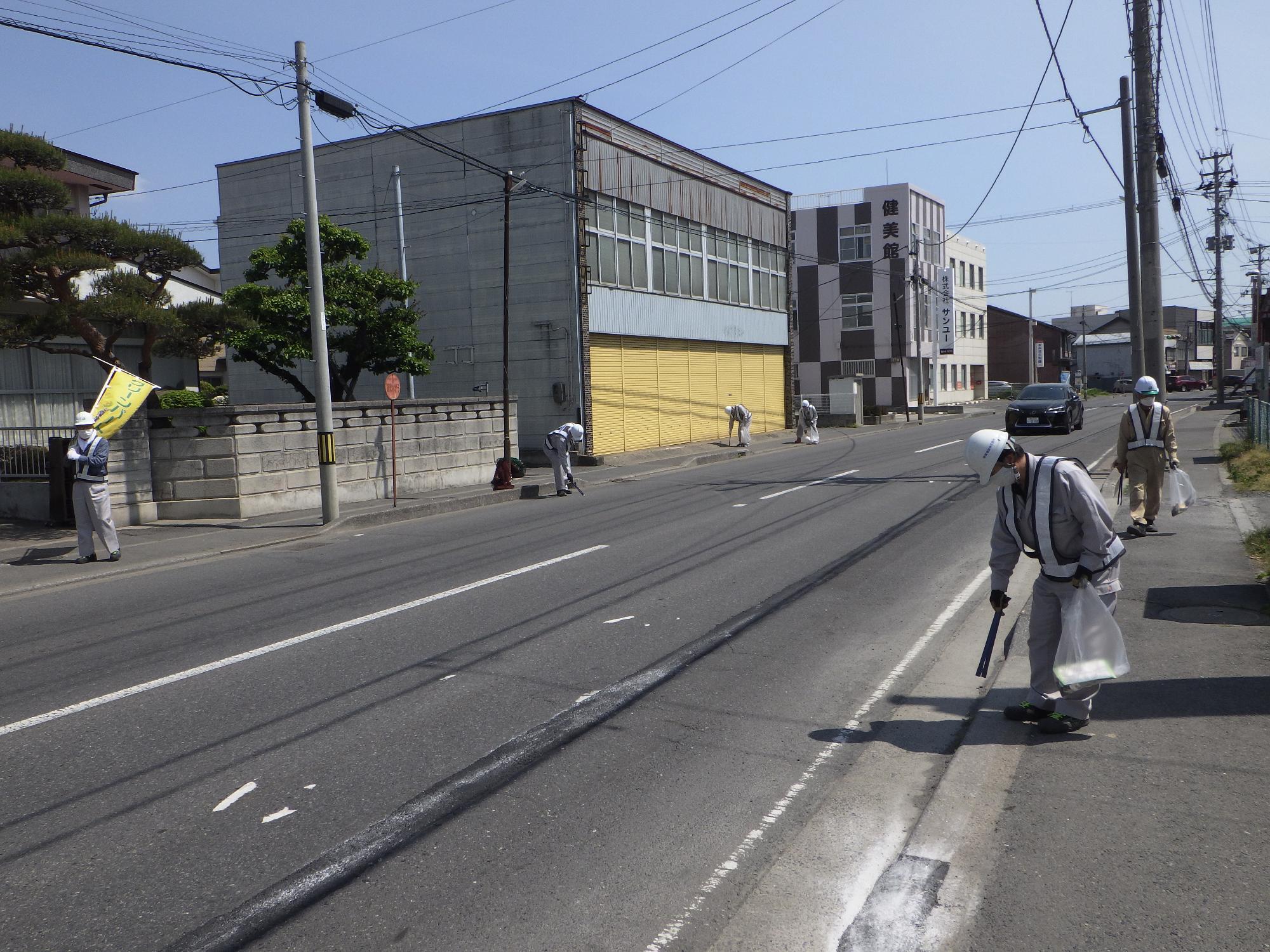 2車線道路の歩道のごみを拾う参加者の皆さん