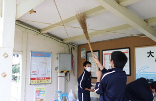 大久喜駅内を竹の箒で掃除している写真