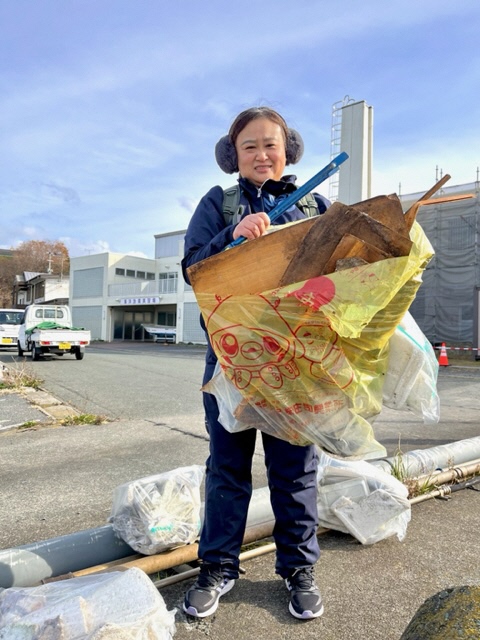 八戸市の指定ごみ袋のなかにベニヤ板が入ったごみを手に持つ女性の写真