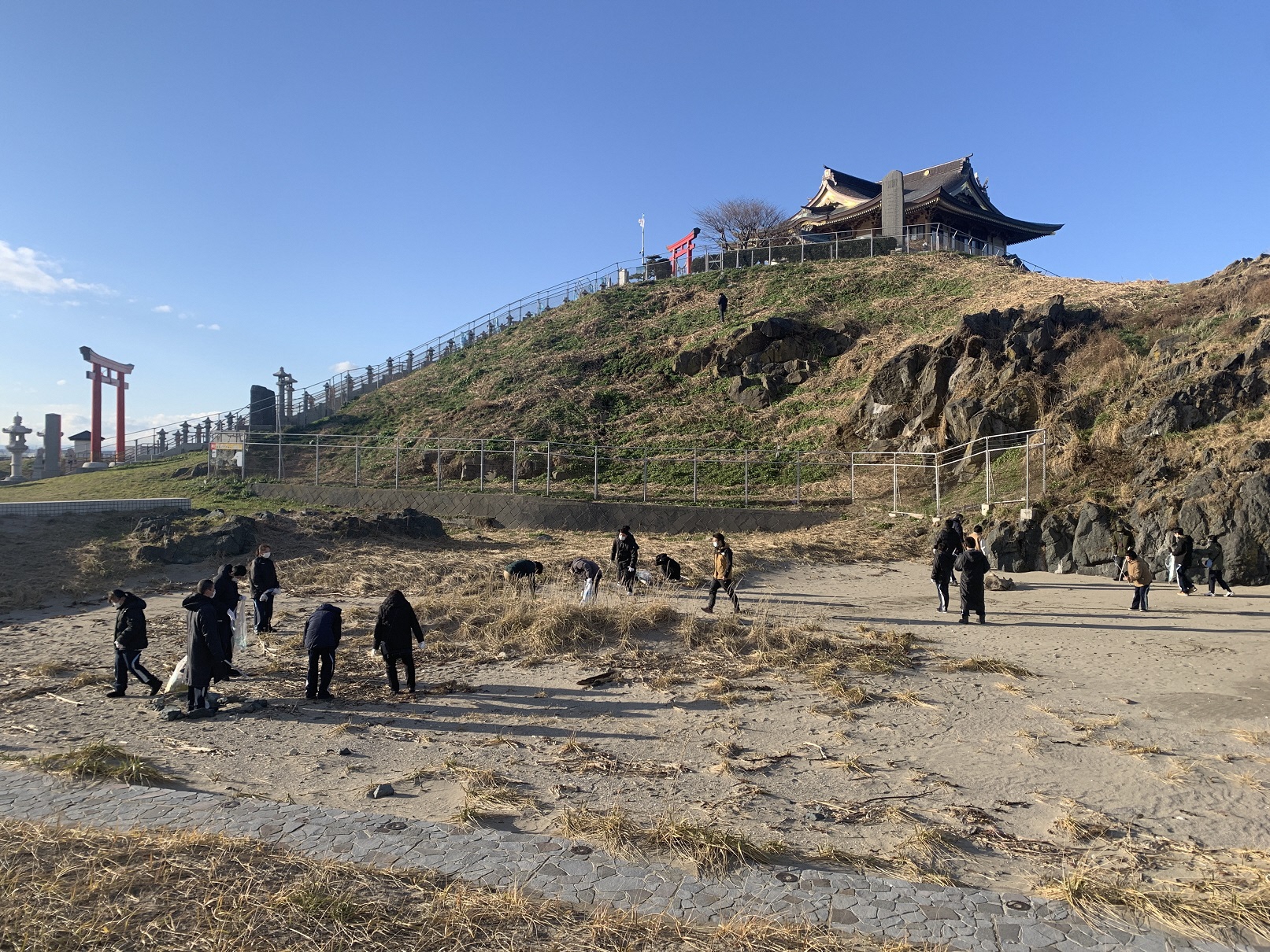 蕪嶋神社の見える砂地でごみを拾っている写真