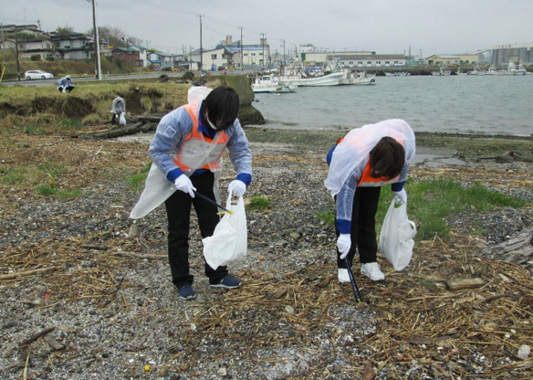 海の見える場所でごみを拾っている二人の写真