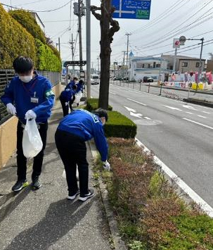 車道脇の草が植えられている場所のごみを拾っている写真