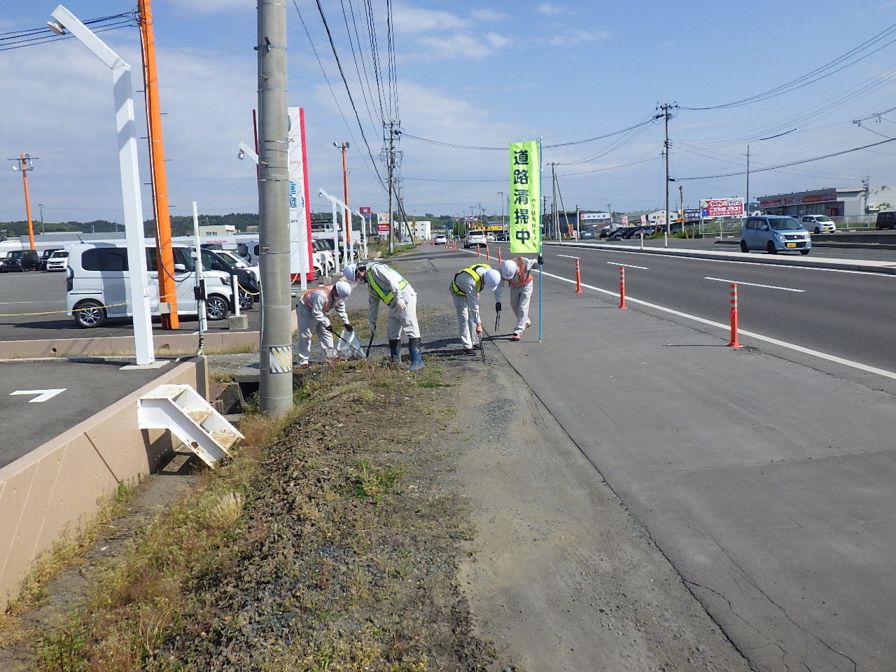 道路清掃中ののぼりを掲げて道路脇のごみを拾っている写真