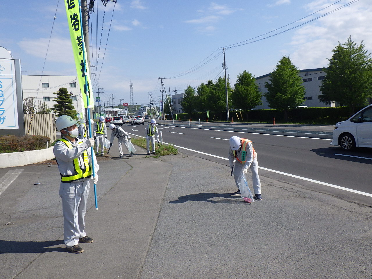 道路清掃中ののぼりを掲げて道路脇のごみを拾っている写真