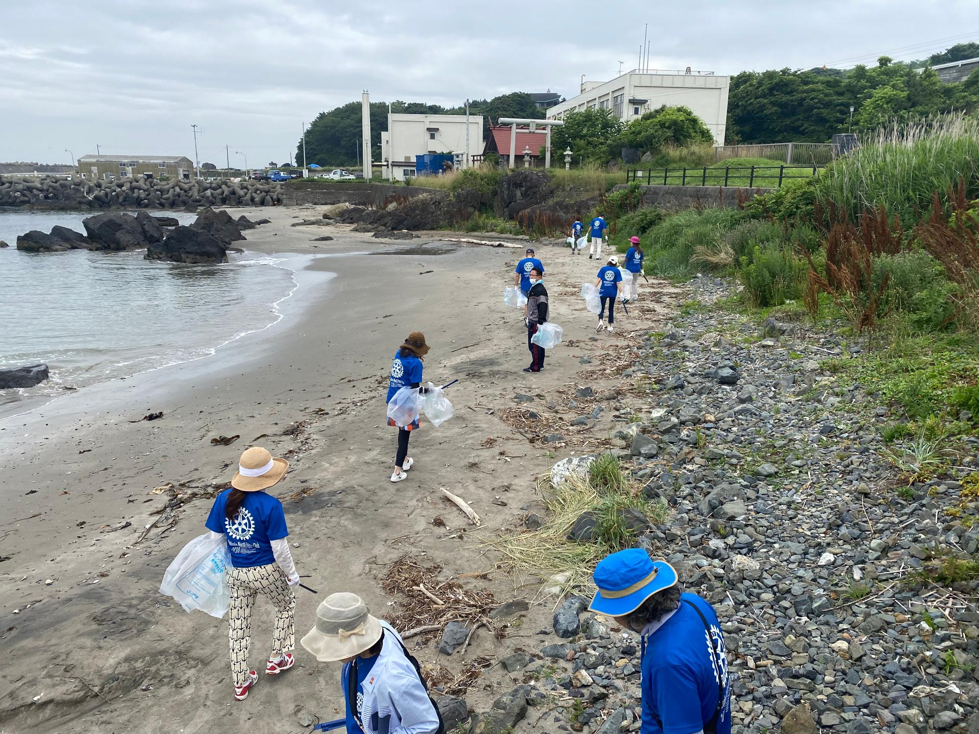 波打ち際の砂浜のごみを拾っている写真