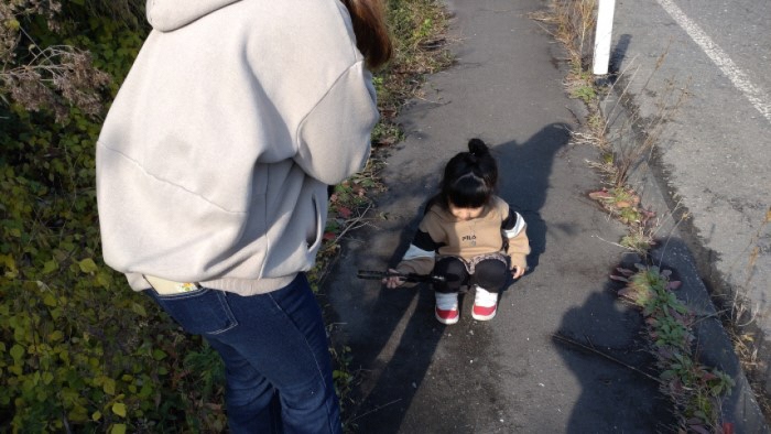 歩道のごみをトングで掴んでいる幼児と大人の写真