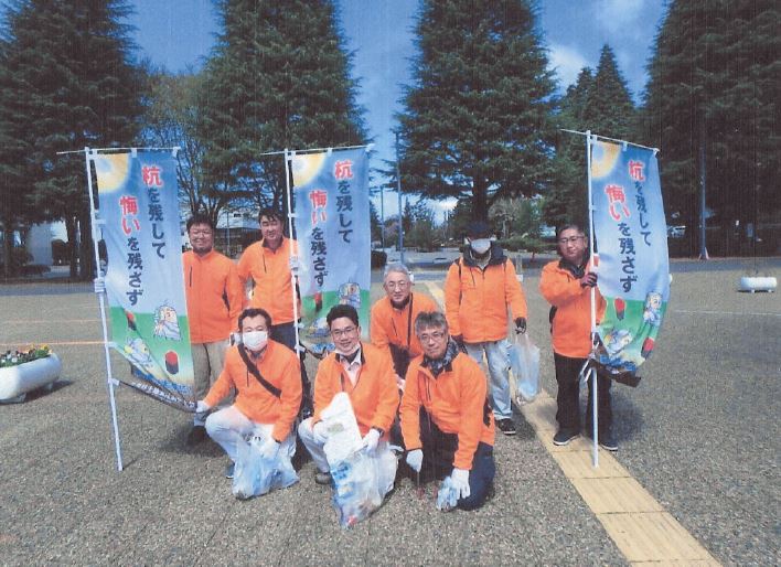 「杭を残して悔いを残さず」と書かれたのぼり旗を掲げて市庁前広場で集合写真
