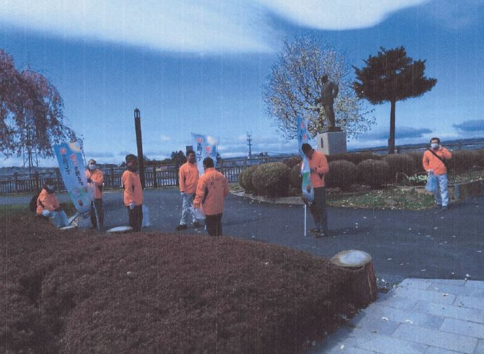 櫻の咲く三八城公園でゴミを拾う全員の写真