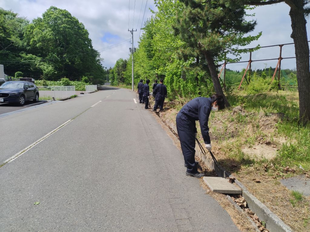 青空の元歩道のごみを拾っている写真