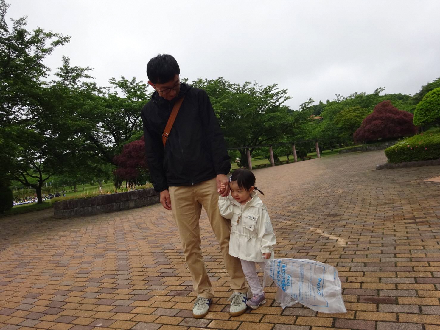 八戸公園内で込みを拾っている女児と男性の写真