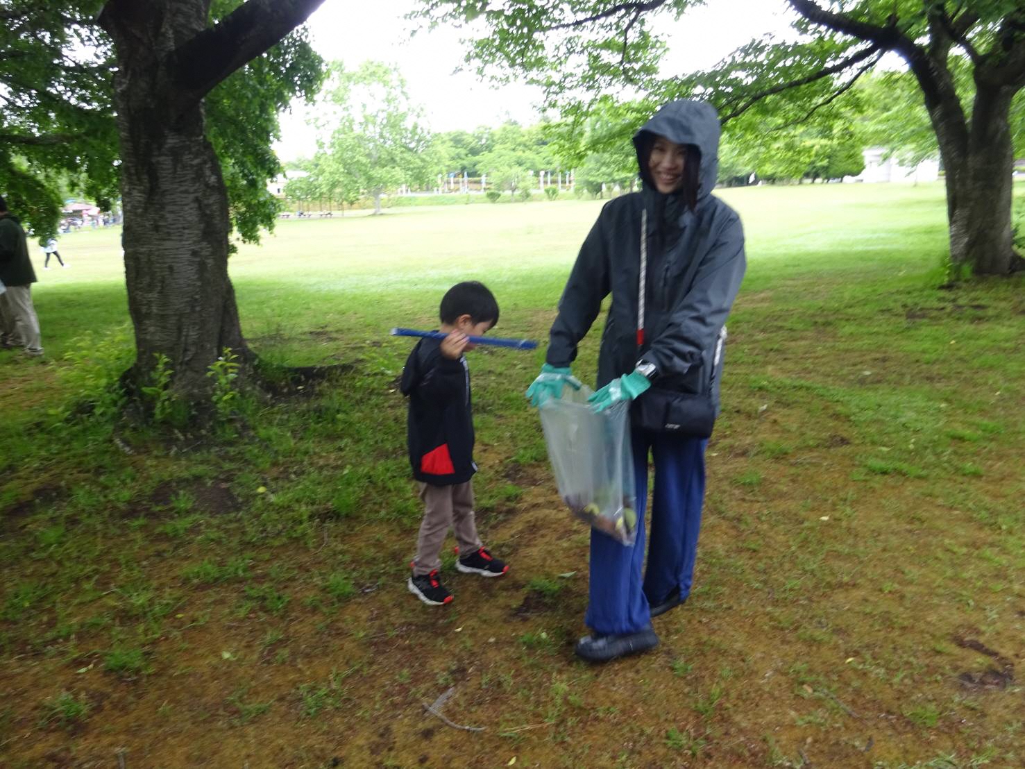 八戸公園内でごみを拾っている男児と男性の写真