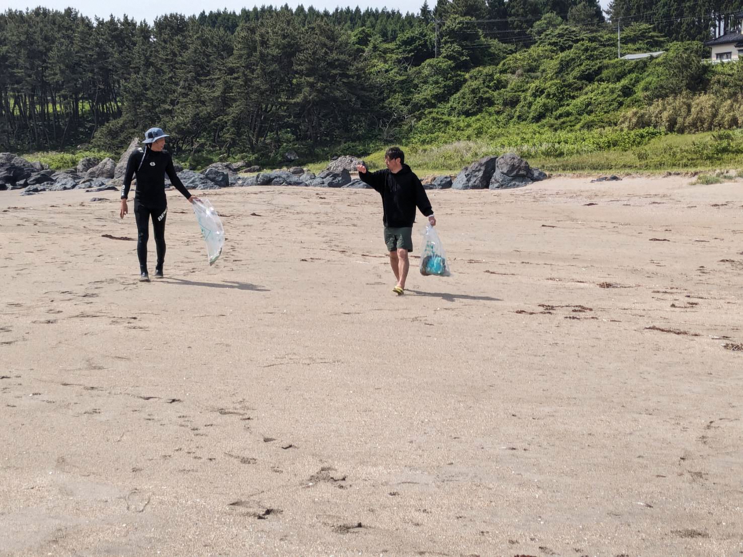 砂浜でごみを拾う人の写真