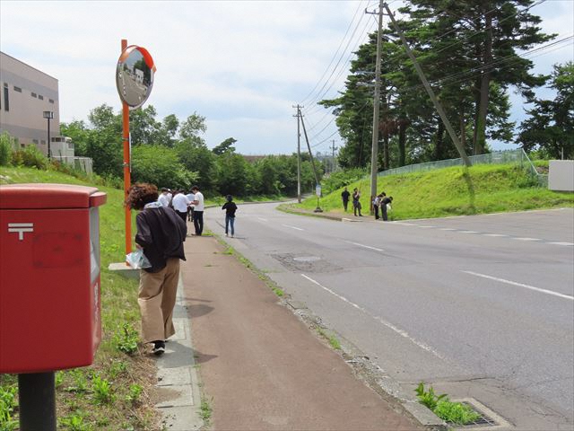 赤いポストのある歩道付近のごみを見つけながら歩いているメンバーの方々の写真