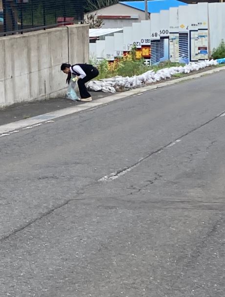 歩道のごみを拾っている女性の写真