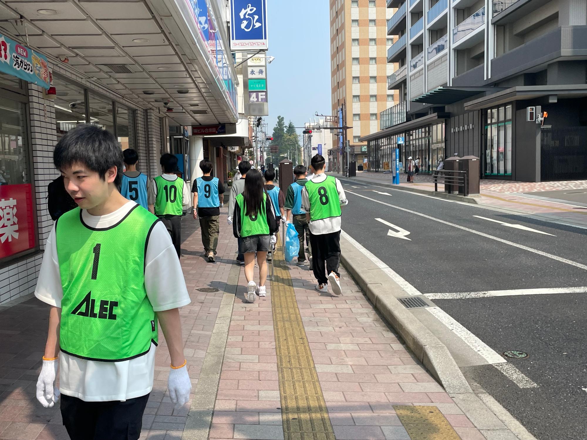 中心街の歩道を歩いているビブスを着用した生徒さんたち