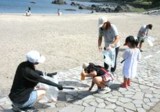 蕪島海水浴場でごみを集めている子どもや女性の写真