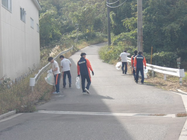 ガードレールのある道路脇のごみを拾っている写真