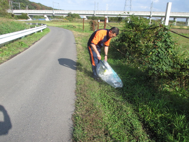 道路脇の草地のごみを拾っている写真