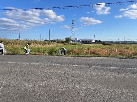 青空の広がる良い天気のもと、歩道のごみを拾う参加者の写真