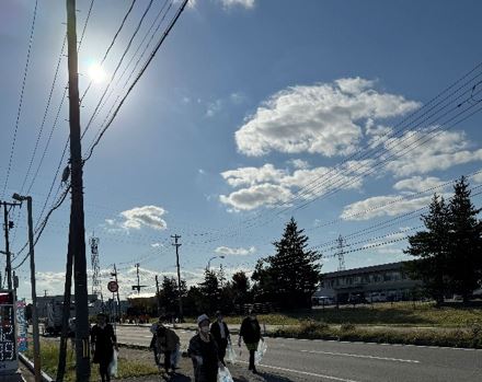 青空の中ボランティア用ごみ袋を手にごみを拾う参加者の写真