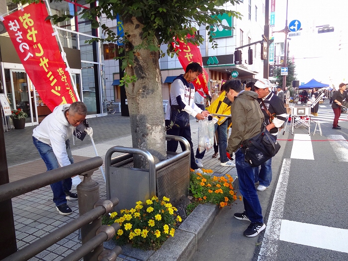 のぼり旗を掲げて歩道のごみを拾っている参加者の写真。