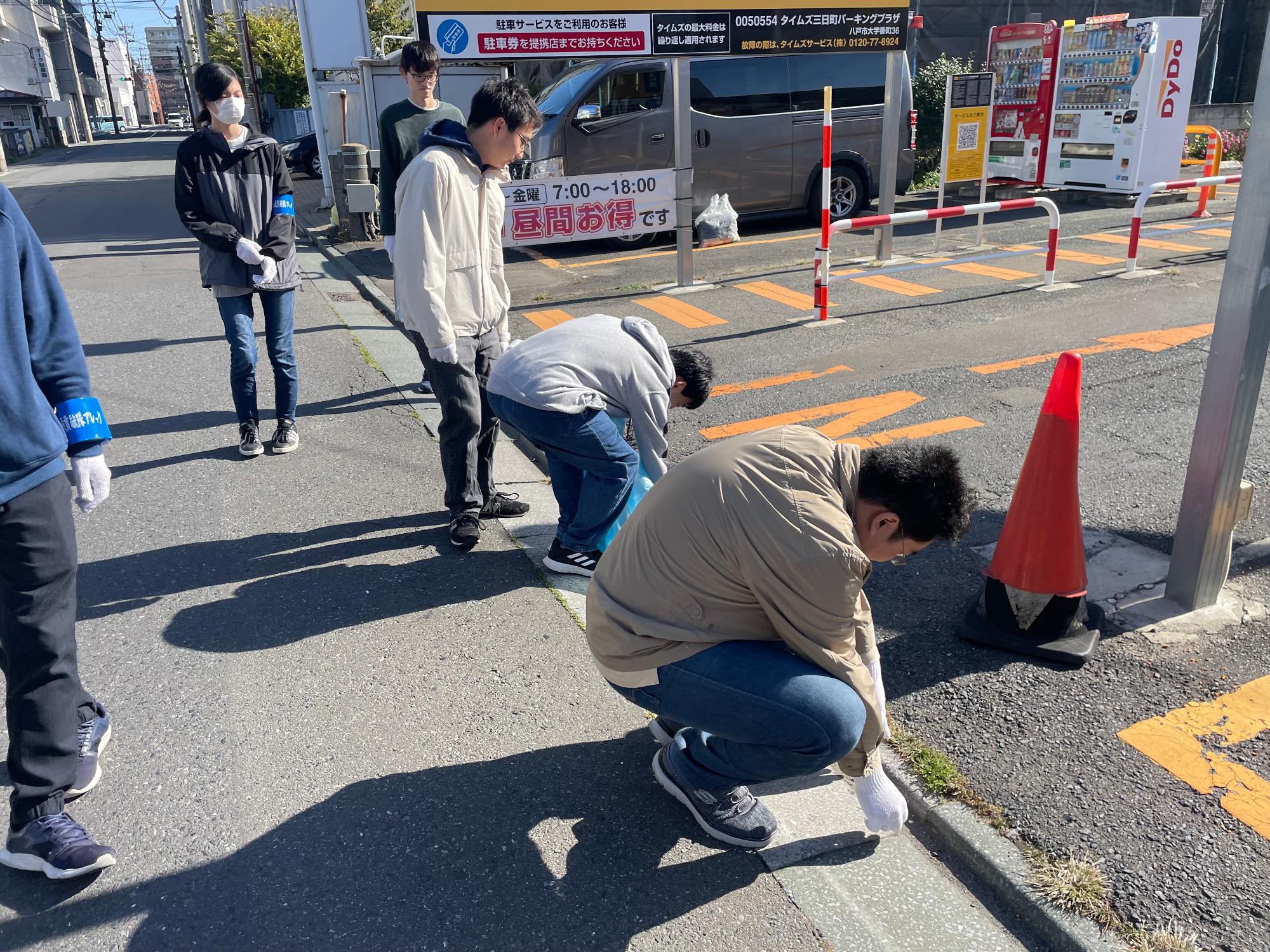 駐車場の周りのごみを拾う参加者の写真