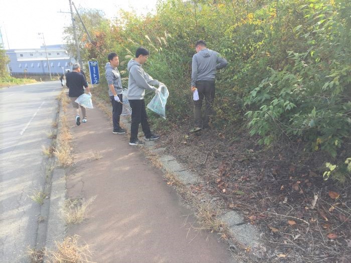 道路脇の草地のごみを拾う写真