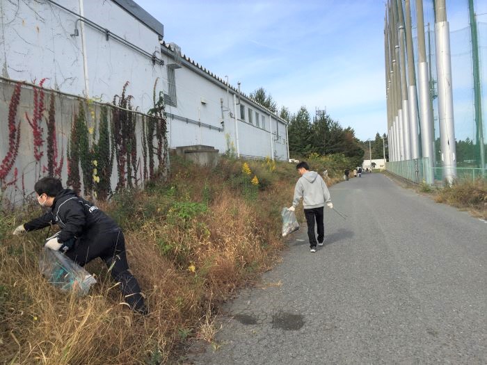 道路脇の草地のごみを拾う写真