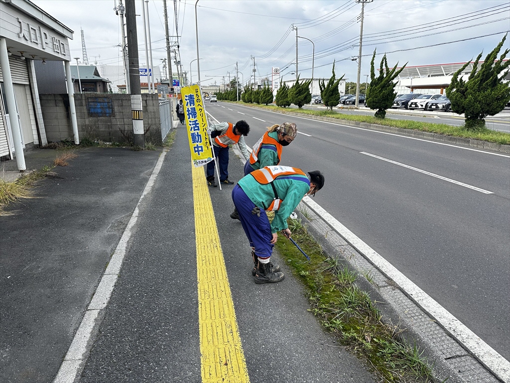 クリーンパートナーの幟を掲げて、ビブスを着用した3人が歩道のごみをトングで拾っている写真。