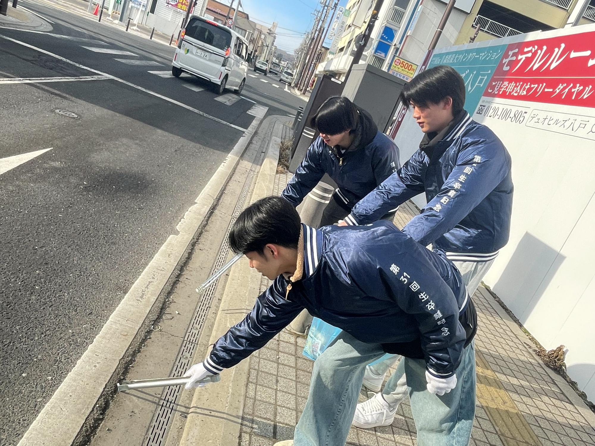 トングで歩道と道路の際のごみを拾っている参加者の写真