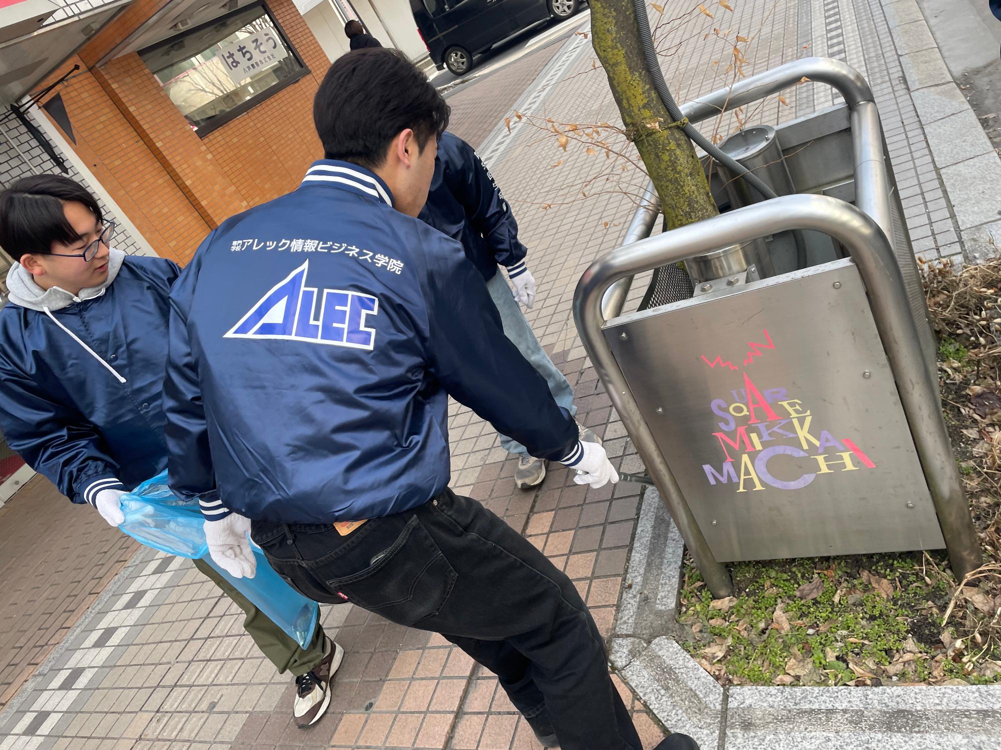 歩道のごみをトングで拾っている男性三人の写真