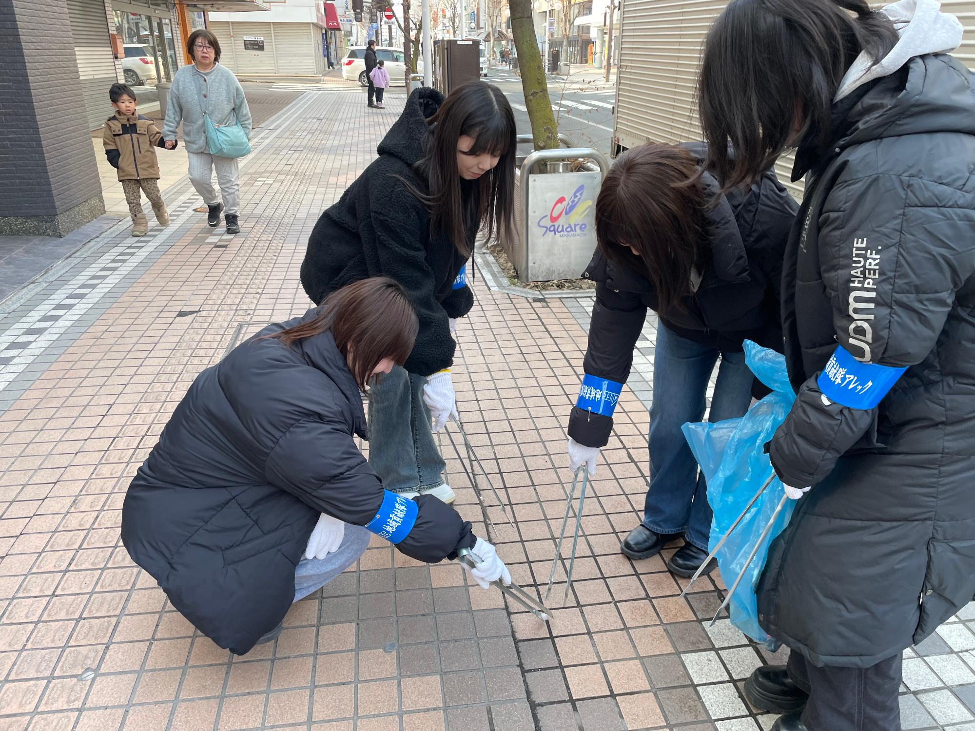 女性四人で歩道のごみをトングで拾っている写真
