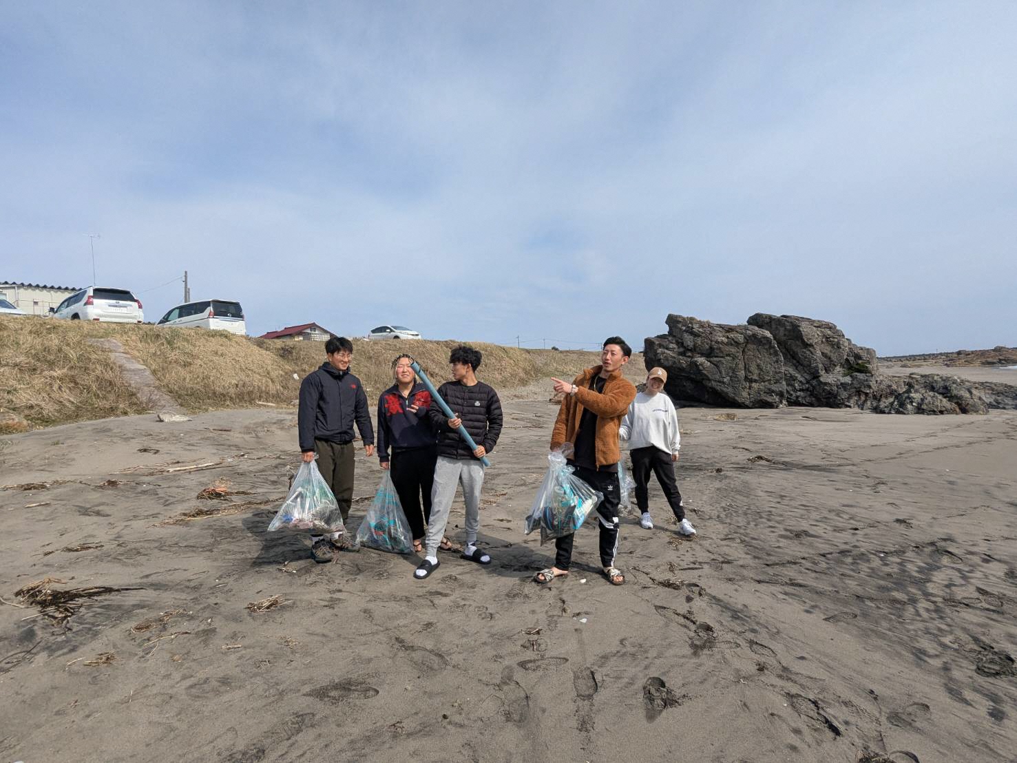 砂浜をごみ袋を持って歩いている様子