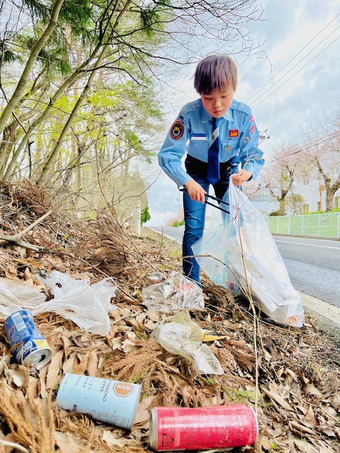道路わきのごみを拾う少年の様子