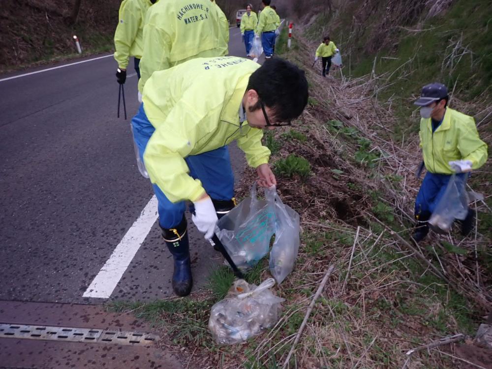 道路脇の草地のごみを拾う写真