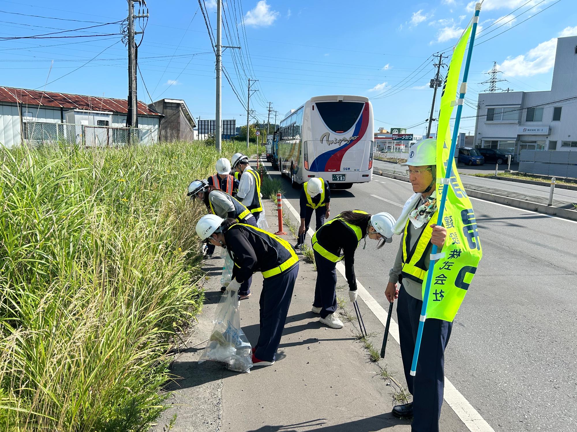 道路脇の草地のごみを拾う写真