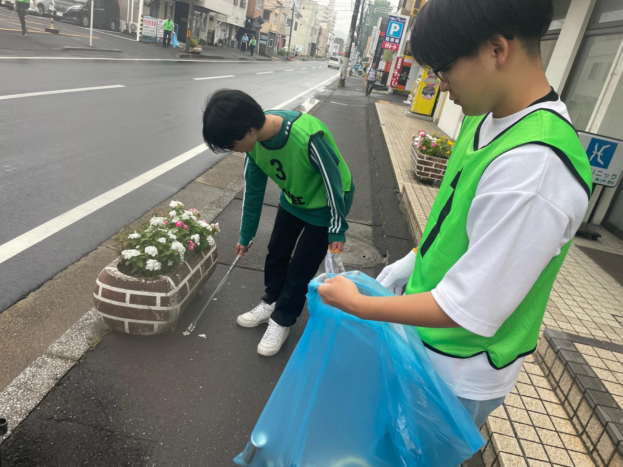 道路脇の草地のごみを拾う写真