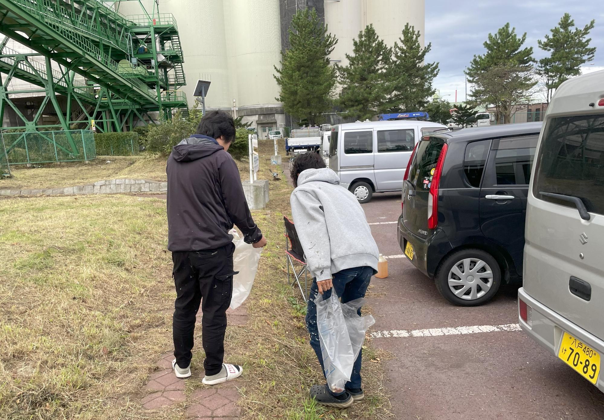 道路脇の草地のごみを拾う写真