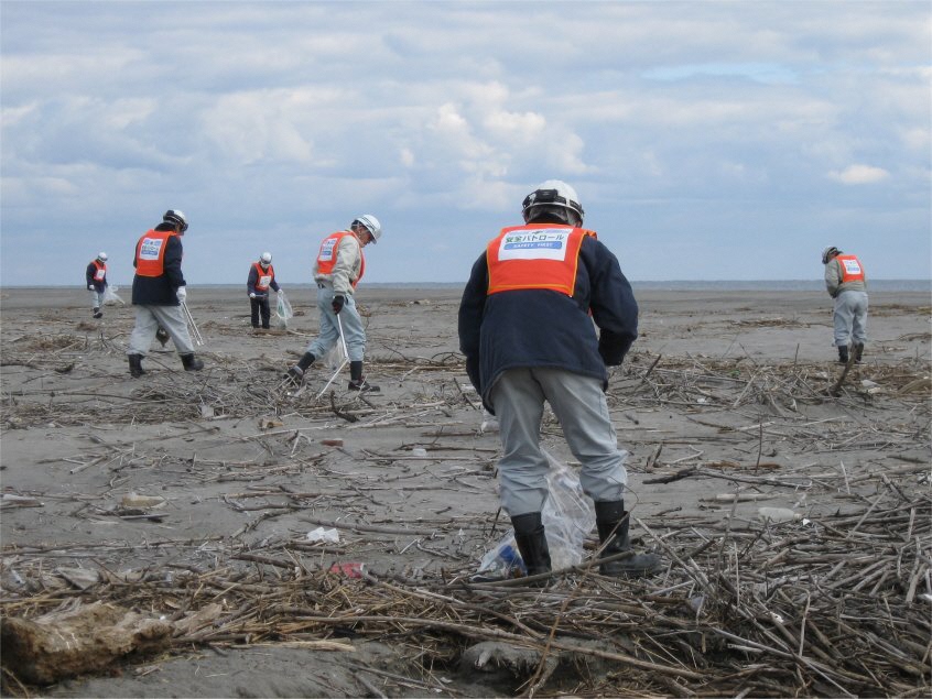 大勢で五戸川河口のごみを拾う様子