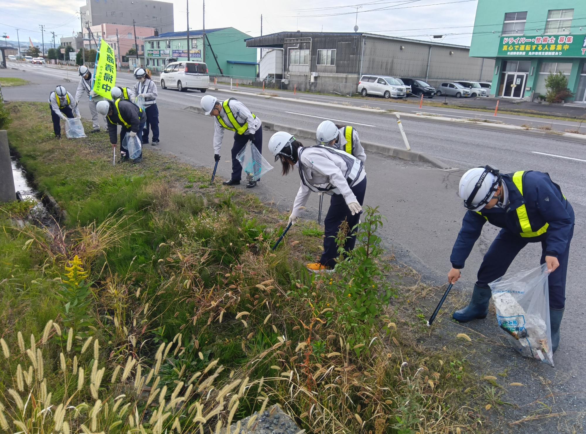 道路脇の草むらのごみを拾っている様子
