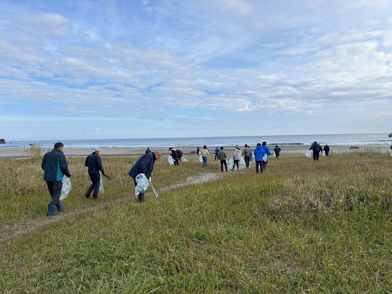 大勢で砂浜のごみを拾っている様子
