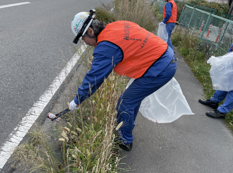 道路と歩道の境にポイ捨てされた缶を拾っている様子
