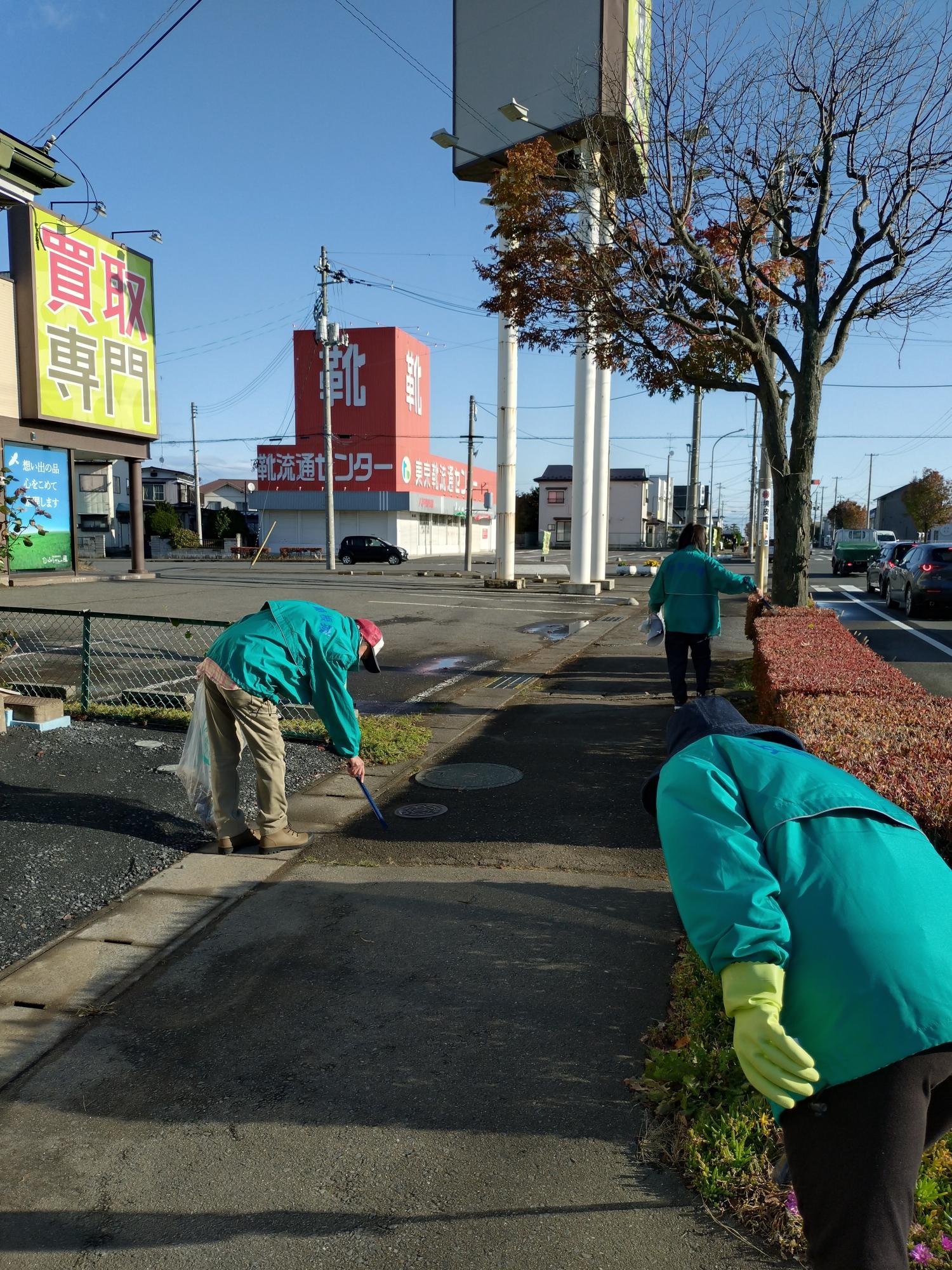 道路脇の歩道のごみを集めている参加者3人の写真2